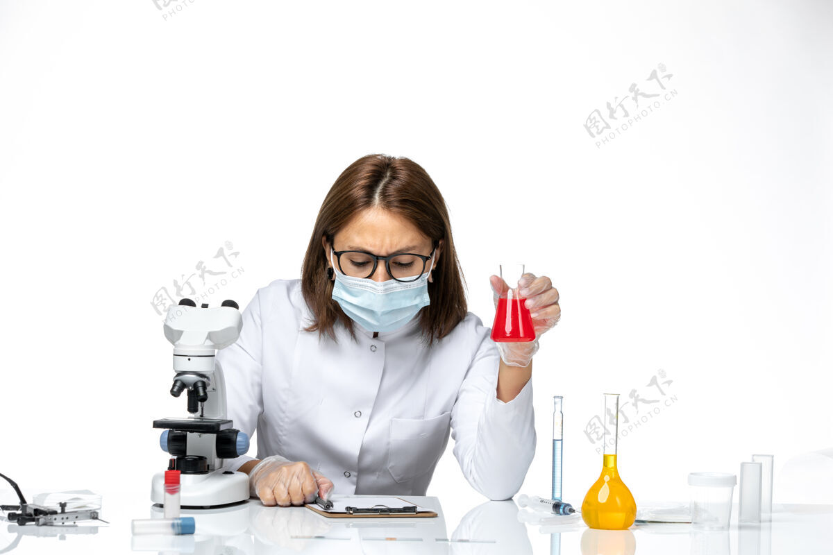 实验室外套前视图穿着白色医疗服的女医生 戴着面罩 因为科维德在浅白的空间里工作医疗到期外套