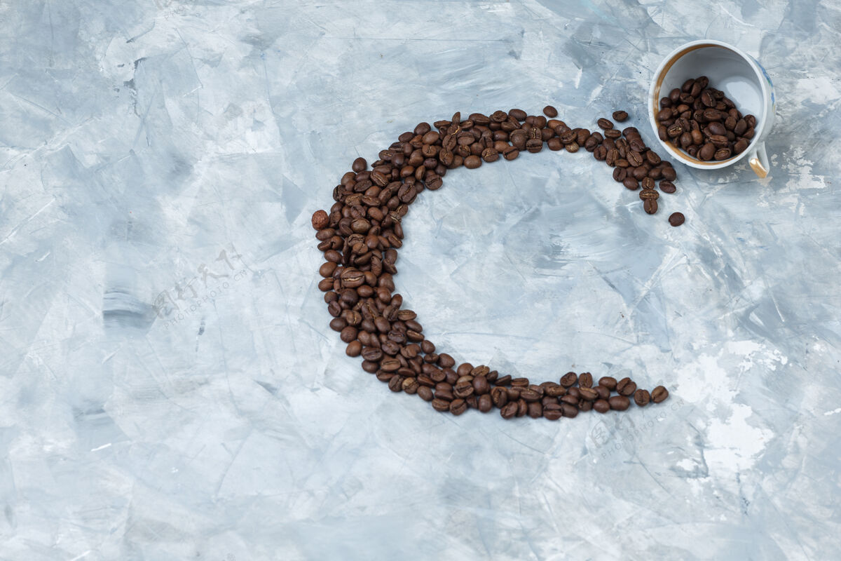 新鲜的咖啡豆在一个灰色灰泥背景上的白色杯子里顶视图农作物咖啡因烤