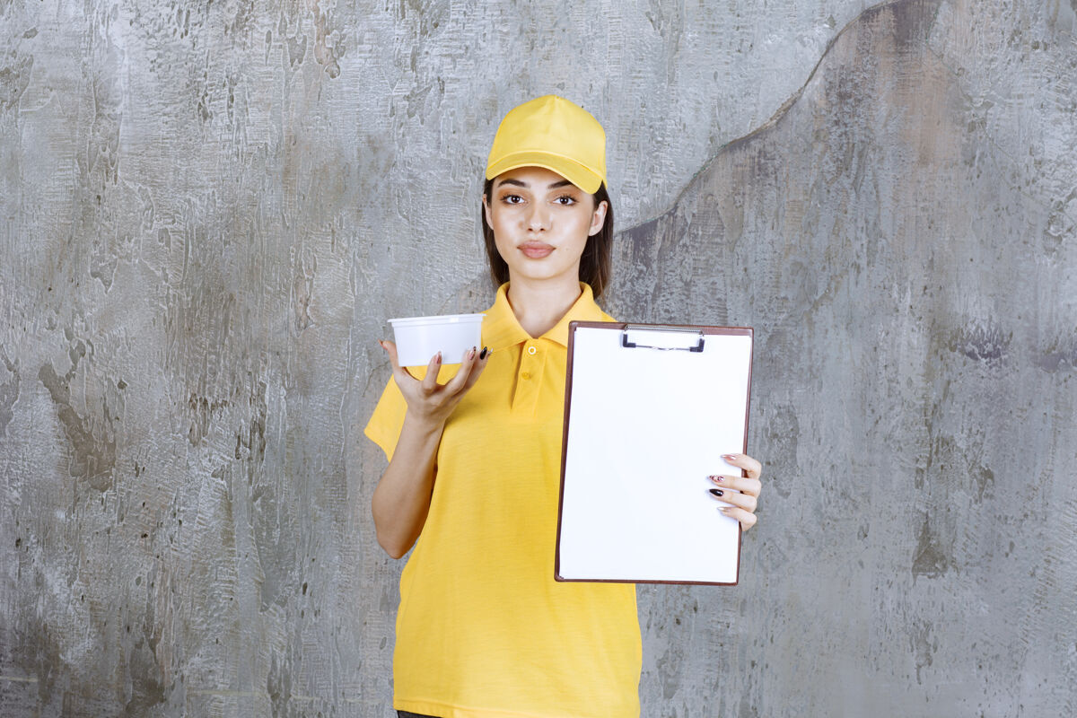 送货穿着黄色制服的女服务人员拿着一个塑料外卖碗 给顾客名单签名姿势货物船运
