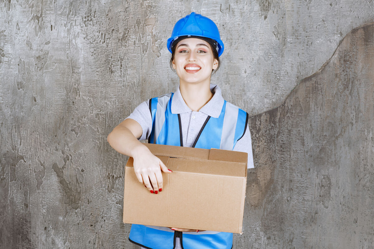 模特身穿蓝色制服 头戴头盔 手持硬纸板包裹的女工程师年轻人工人成人