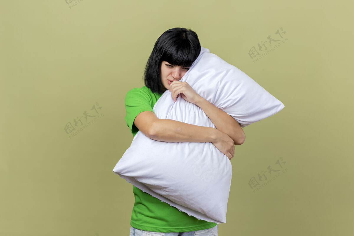 奥利弗疼痛的年轻白种人女孩抱着枕头 在橄榄绿的墙壁上看着孤立的复制空间拥抱年轻疾病