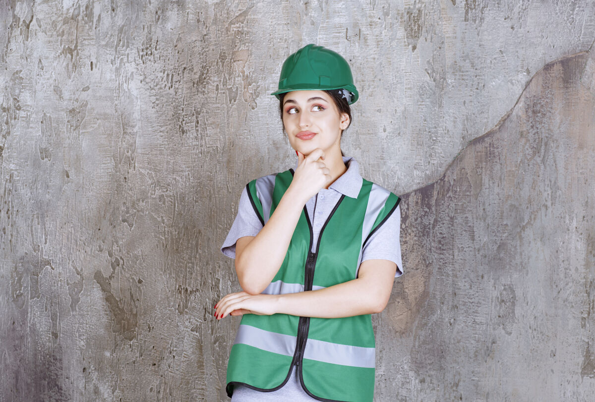 工作场所身着绿色制服 头戴安全帽的女工程师看上去既困惑又体贴模特人体模型不确定