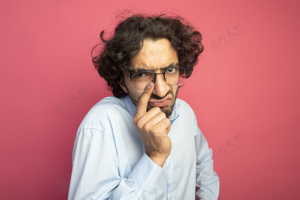 眼镜皱眉的年轻英俊的白人男子戴着眼镜把手指放在鼻子上 隔离在深红色的墙上 留着复印空间鼻子深红色男人