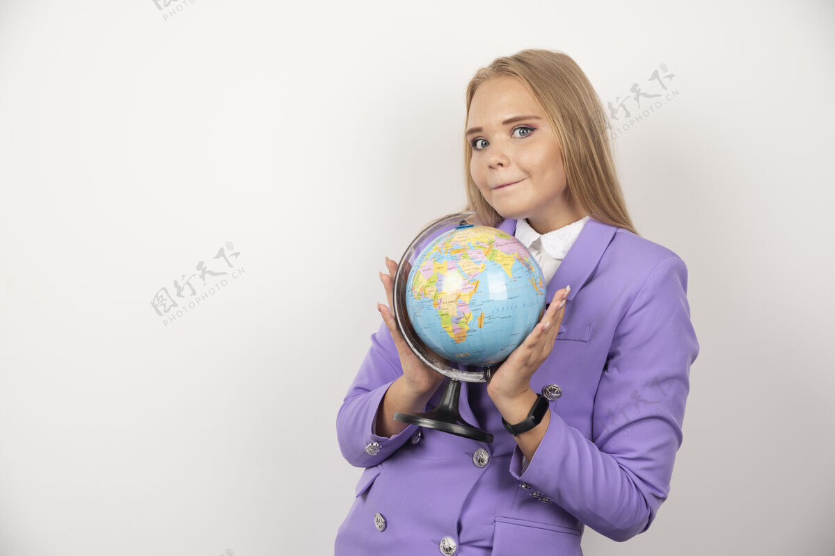 工作美丽的老师拿着地球仪在白墙上老师教育女人