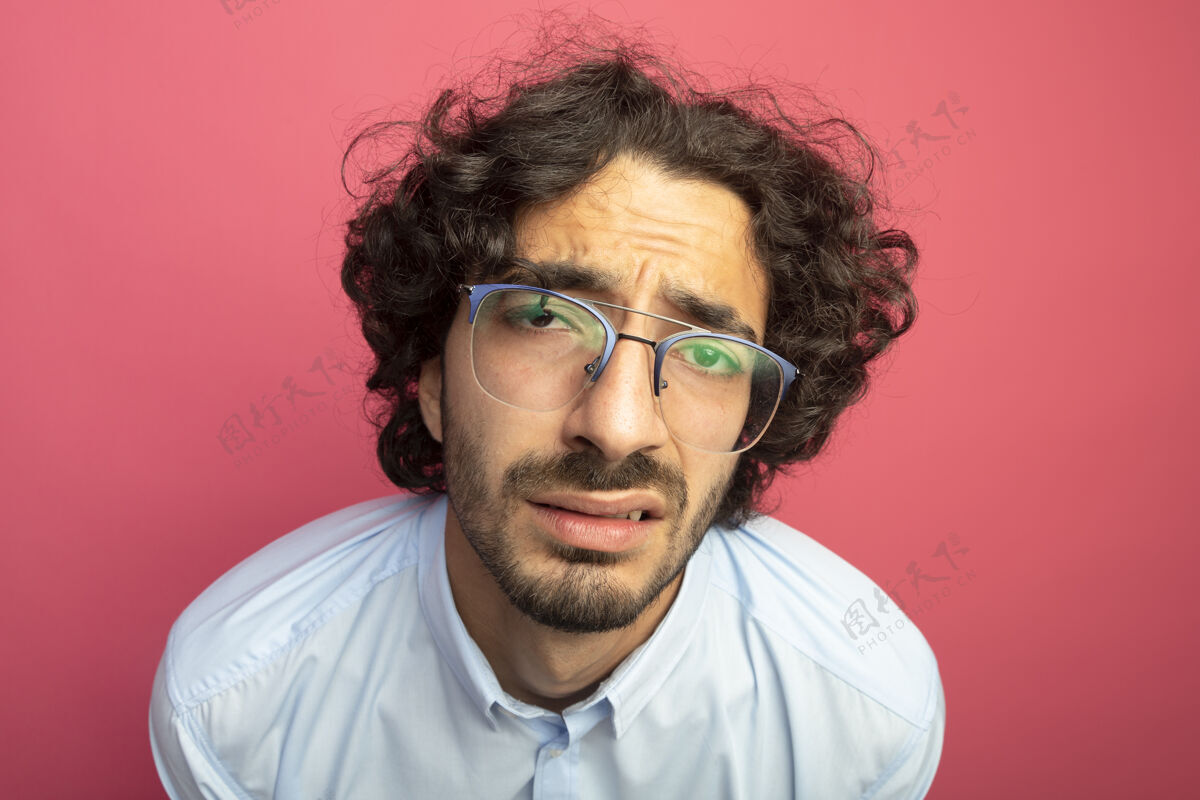 令人不快特写镜头 年轻英俊的白人男子戴着一副深红的眼镜 孤零零地站在墙上男人特写年轻