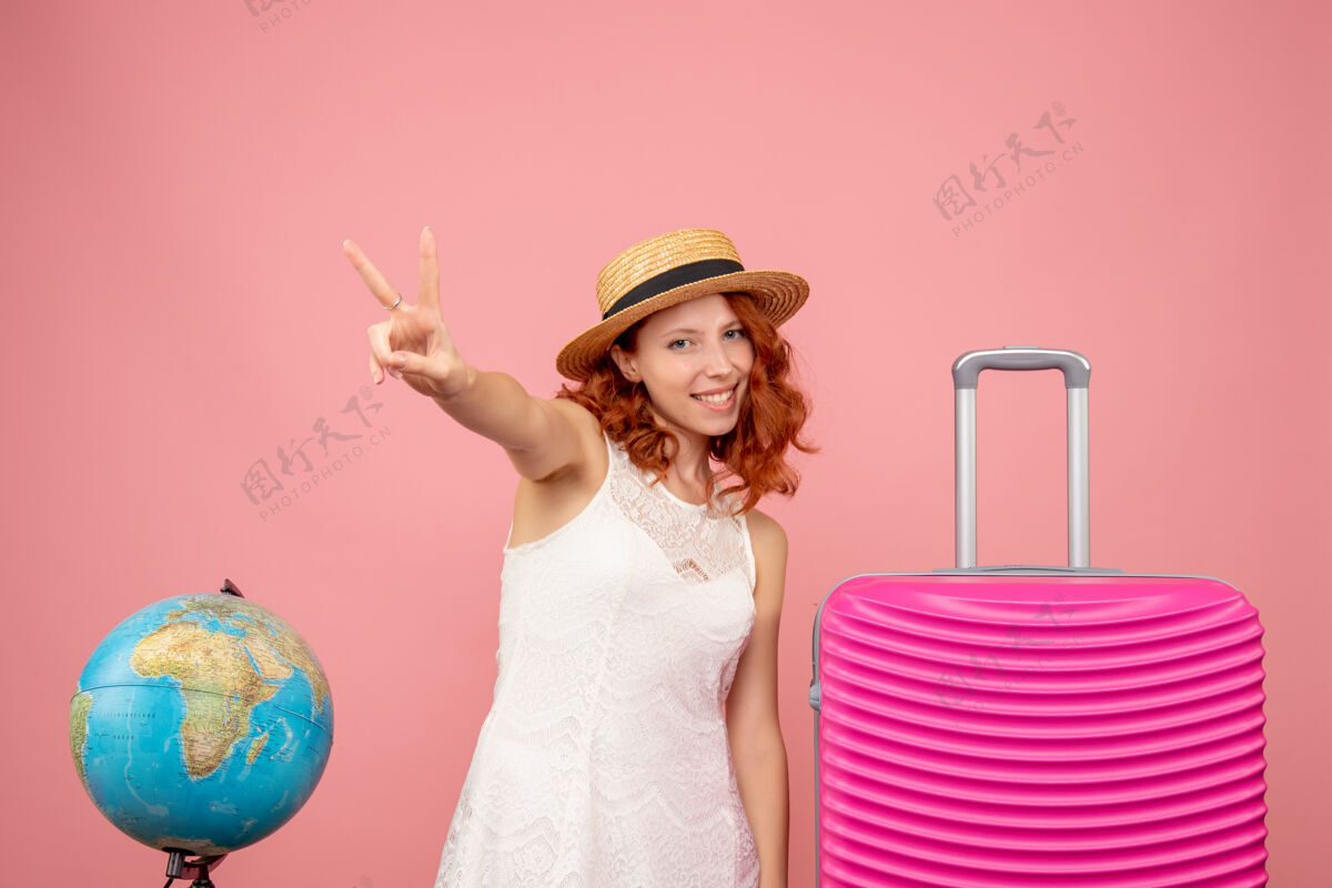 快乐年轻女性游客的正面图 粉红色的墙上挂着粉红色的包旅行人包