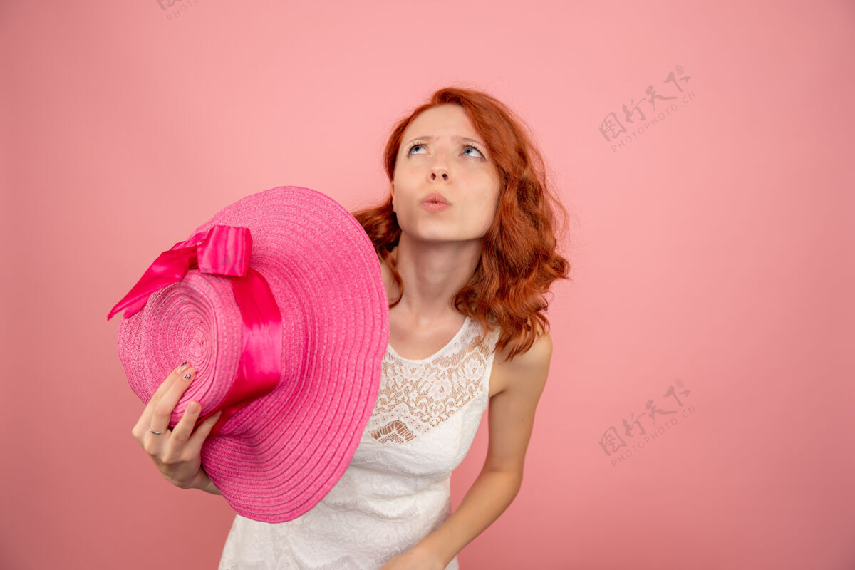 女人在粉红色的墙上戴着粉红色帽子的年轻女性的正视图微笑前面假期