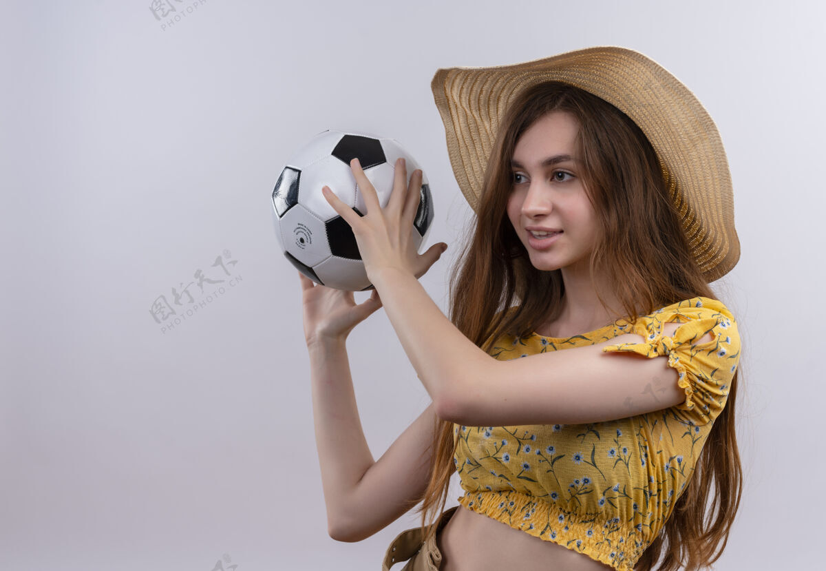 女孩带着微笑的年轻女孩戴着帽子拿着足球在隔离的白色墙上复制空间女人足球抱着