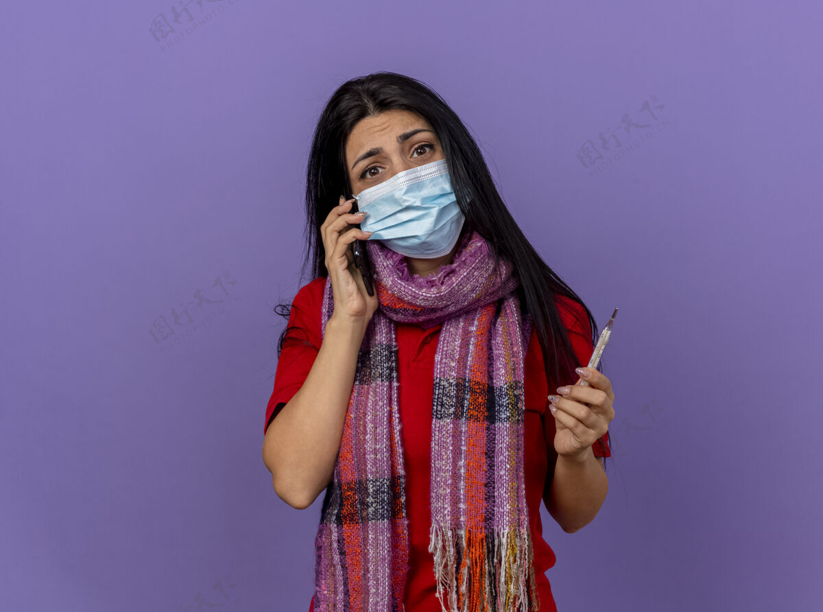疾病焦急的年轻白种人病女孩戴着面具和围巾拿着温度计隔离在紫色的墙上 留着复印空间体温计焦虑年轻