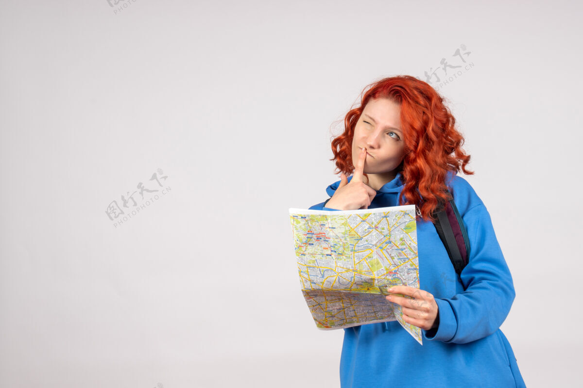 背包年轻女性的正面图 白色墙上有背包和地图情感航程快乐
