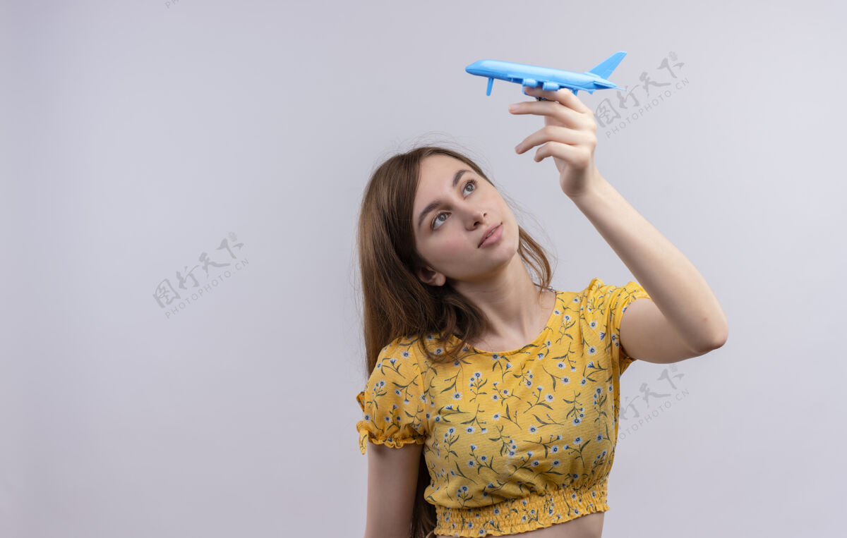 女人年轻女孩举起模型飞机 看着它在孤立的白色墙壁与复制空间举起来飞机年轻人