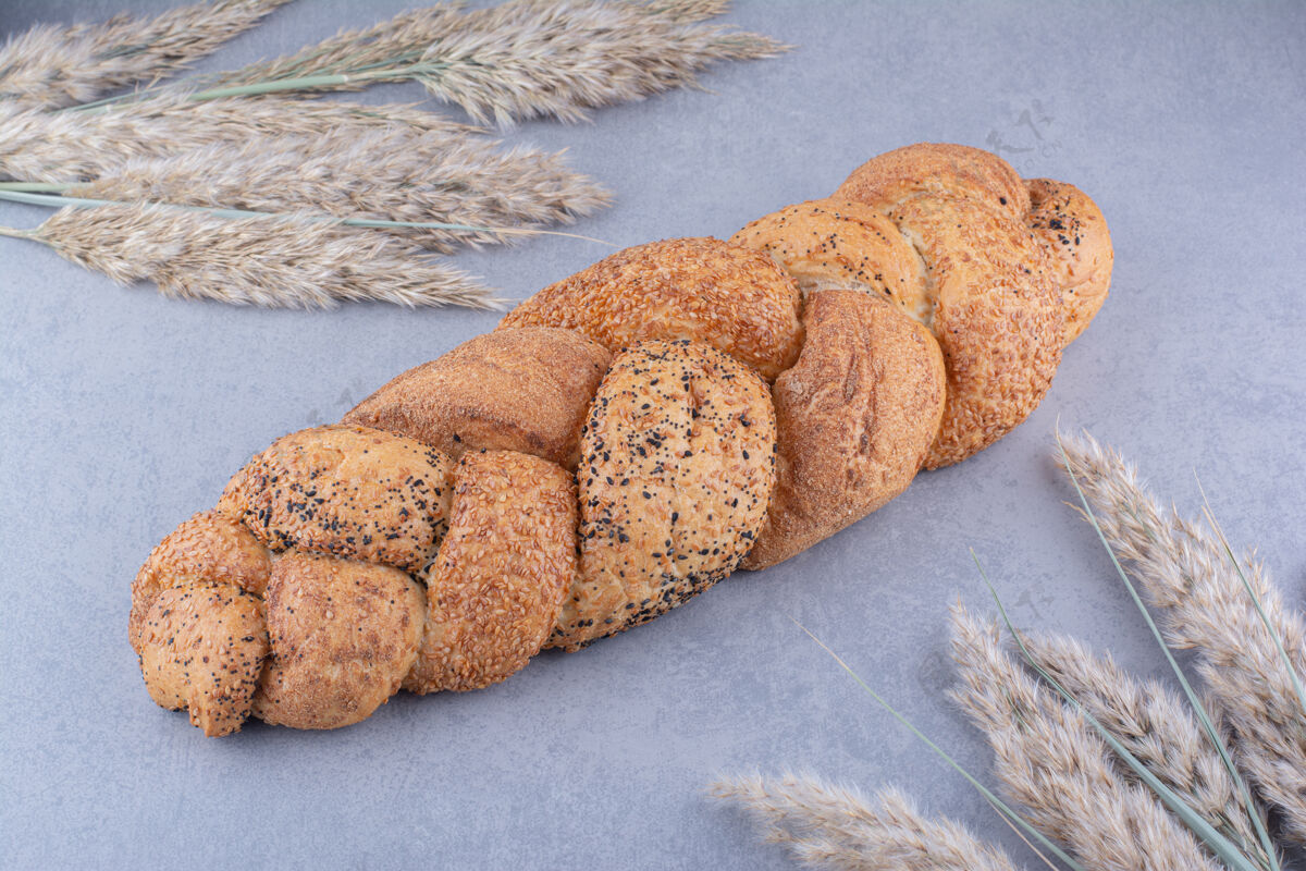 酵母在大理石表面装饰性的干羽毛草茎中的斯特拉西亚面包面包面粉芝麻