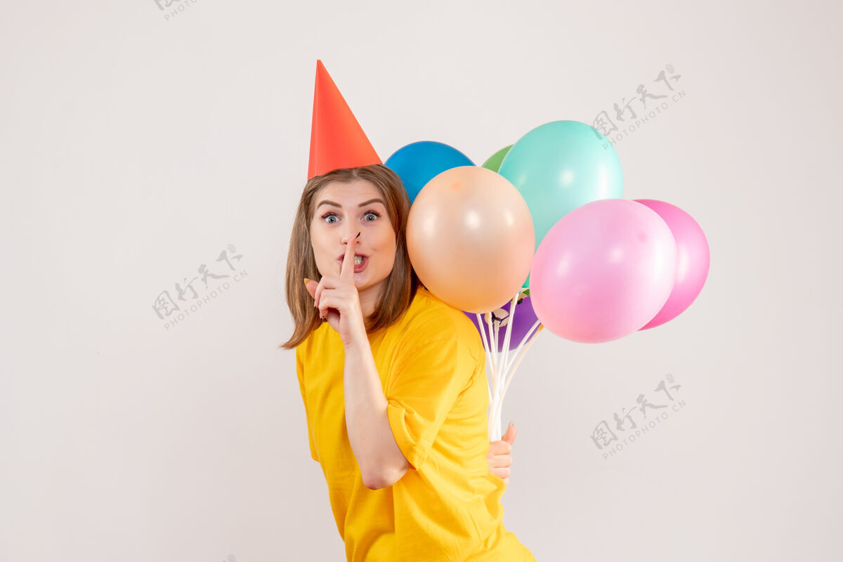 年轻女性年轻的女性把彩色的气球藏在白色的背上乐趣情感回来