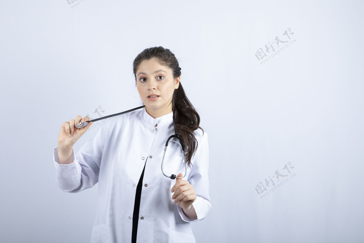 女人穿着白大褂的漂亮医生在白墙上显得很惊讶医生医生听诊器