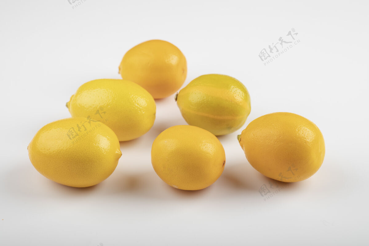 酸味白色桌子上放着新鲜成熟的黄色柠檬柠檬异国风味新鲜