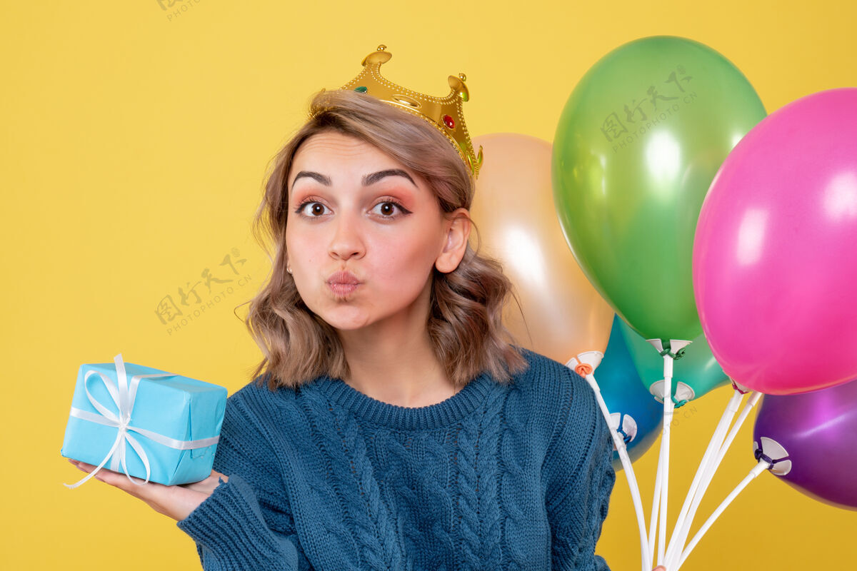 乐趣年轻的女性拿着气球和黄色的小礼物举行圣诞节黄色
