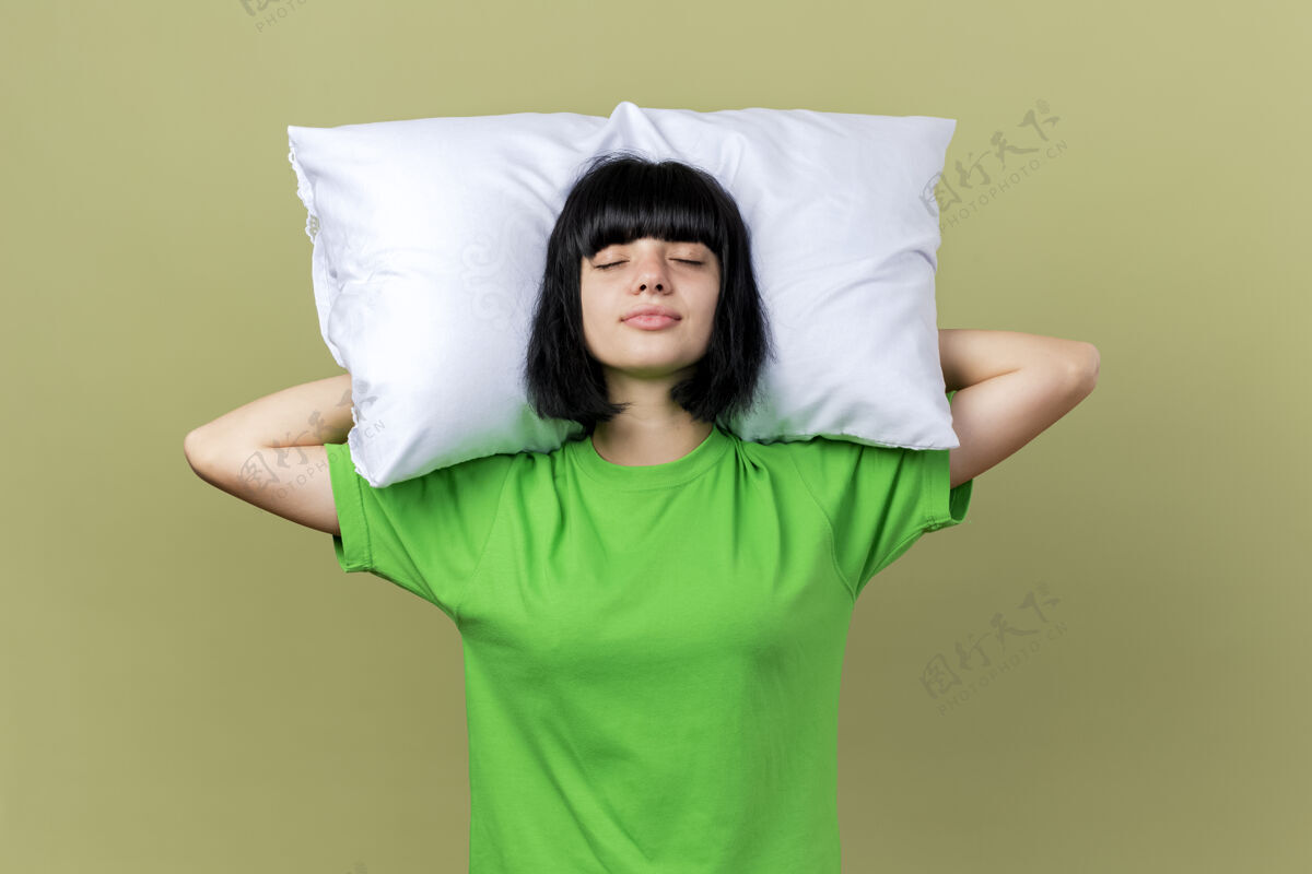 橄榄年轻生病的白人女孩抱着枕头在头下 闭着眼睛孤立的橄榄绿背景疾病眼睛女孩