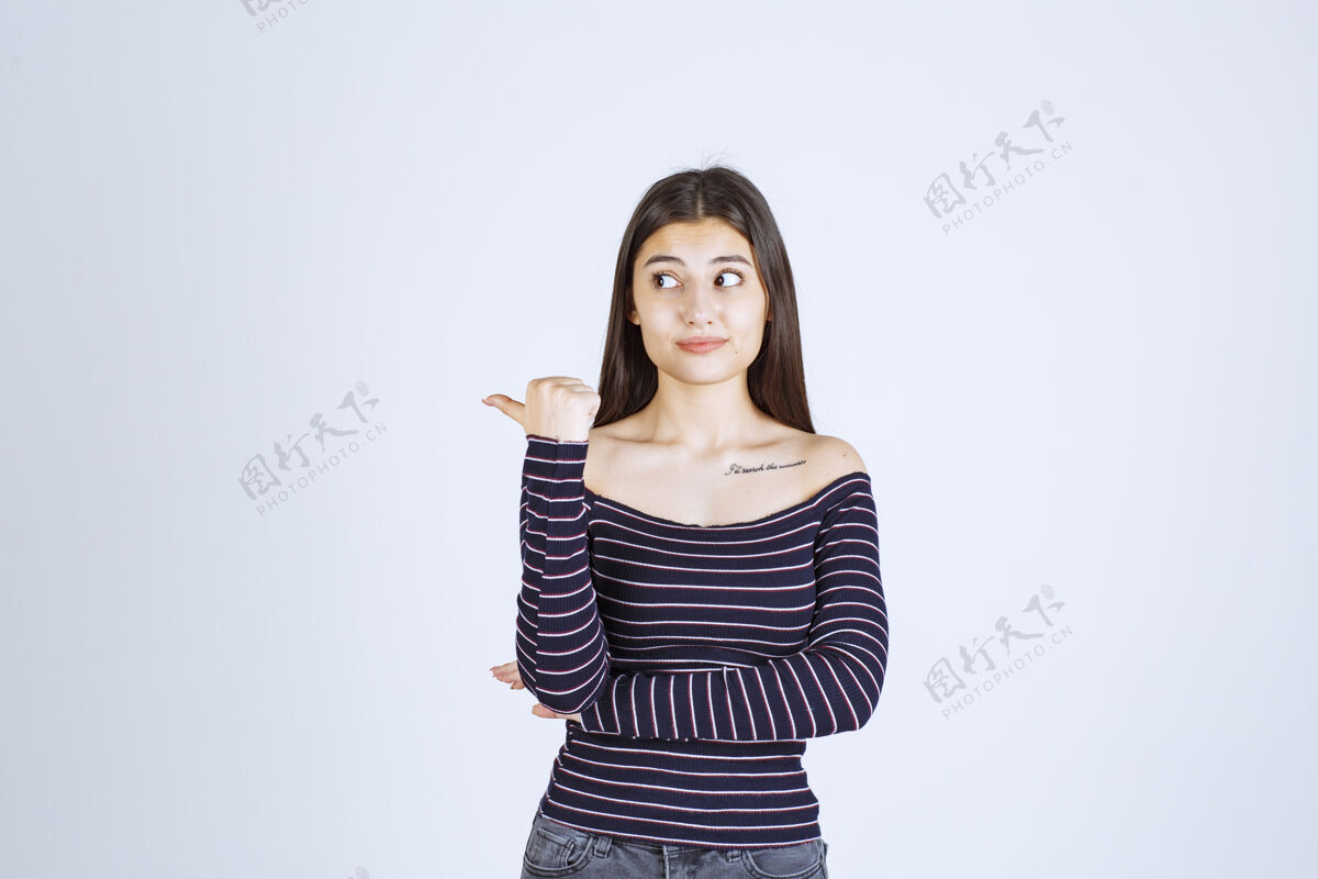 人穿条纹衬衫的年轻女子指着后面的东西方向休闲位置