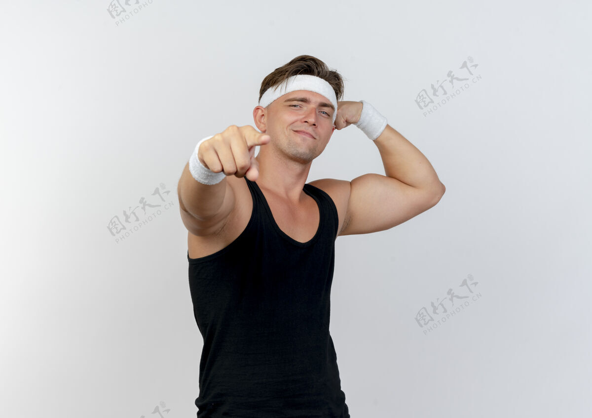 英俊自信的年轻帅气的运动型男人戴着头带和腕带 有力的手势 指着白色的空白处年轻复制腕带