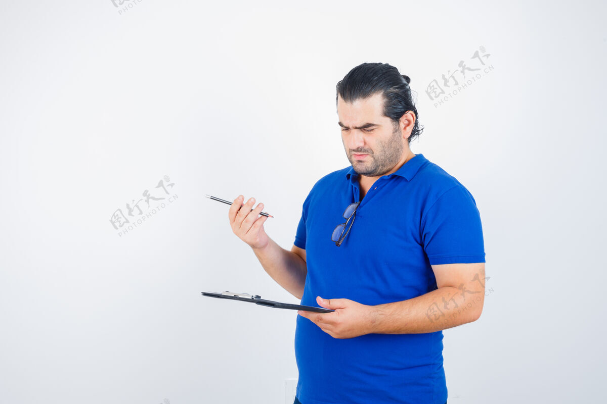 现代一幅中年男子穿着马球衫拿着铅笔 一边看着剪贴板 一边沉思的前视图的画像肖像单身男性