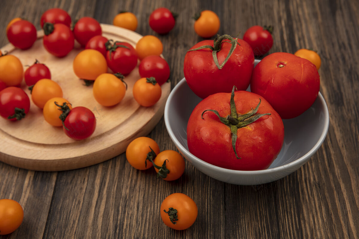 视图顶视图红色和橙色樱桃西红柿隔离在一个木制的厨房板上 大尺寸的西红柿放在一个木制的墙上的碗上新鲜番茄有机