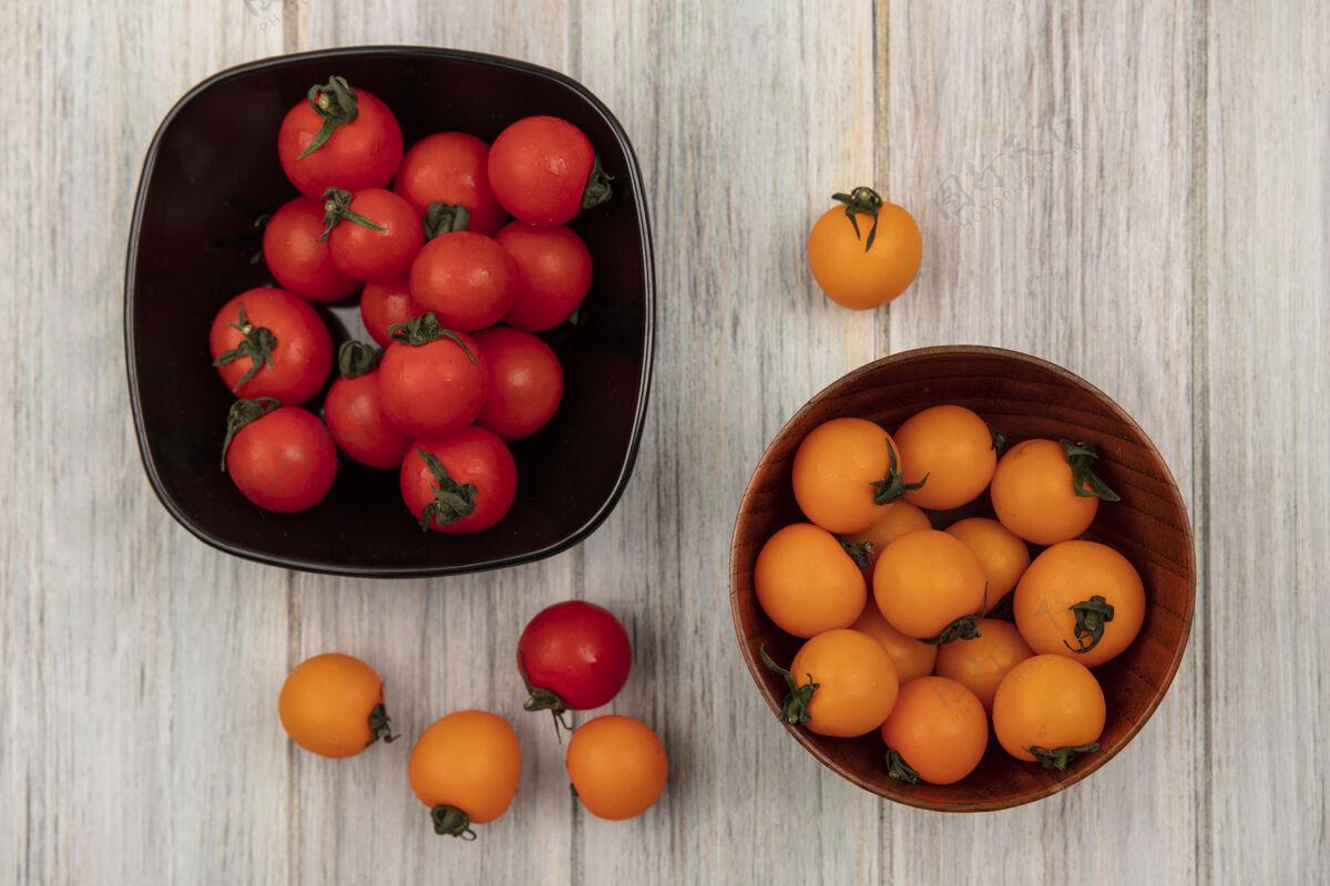 农业新鲜的橙色西红柿放在木碗上 红色西红柿放在灰色木墙上的黑色碗上顶部景观新鲜
