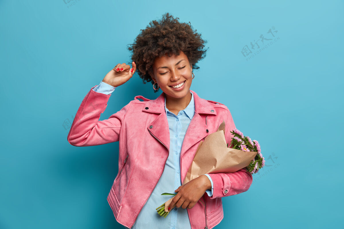 女性欢快无忧无虑的民族妇女欢快地跳舞 手里拿着包在纸里的花束束夏天礼物