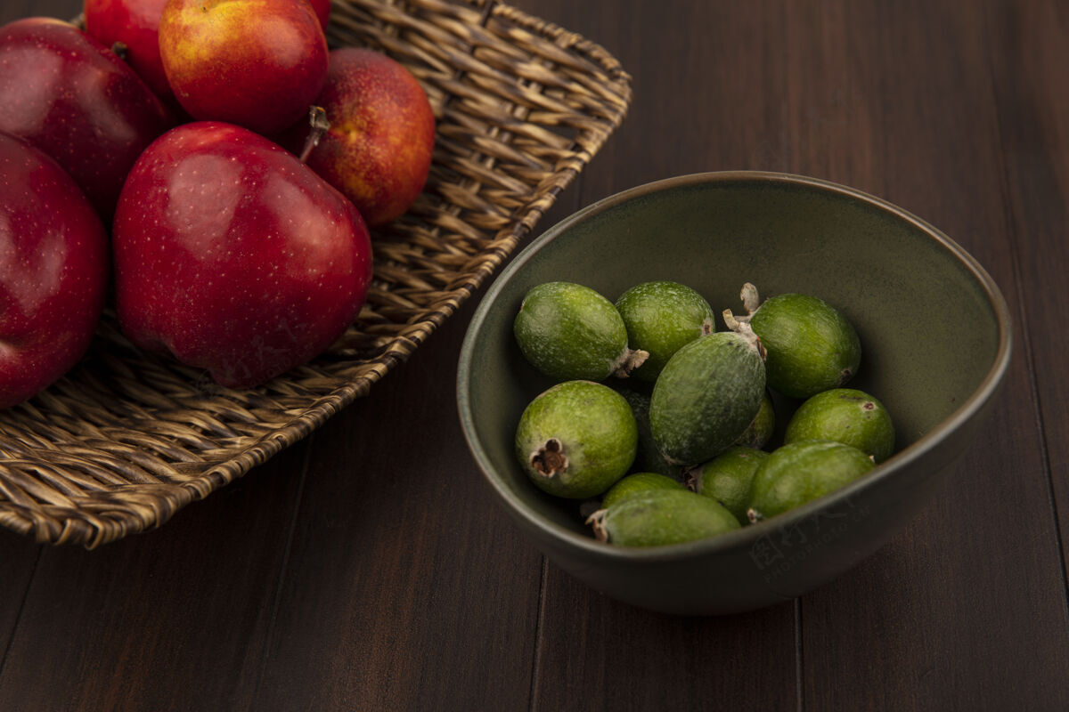 新鲜柳条托盘上新鲜苹果的俯视图 木制墙上的碗上有飞珠托盘木材特写