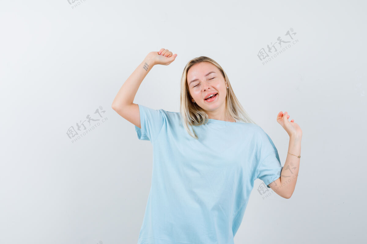 女人金发女孩穿着蓝色t恤展示赢家的姿态 看起来很欢快 正面视图天空快乐女性