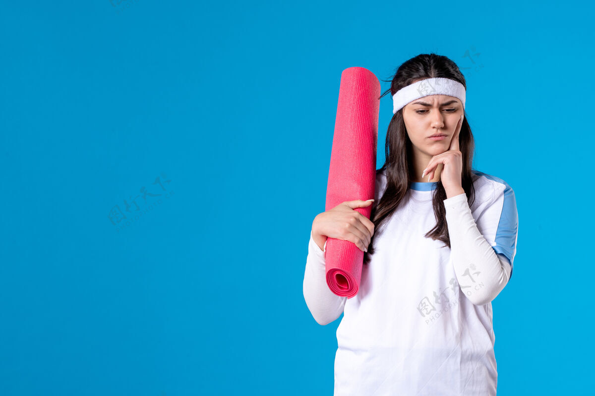 正面前视图：年轻女性 带着地毯在蓝色墙壁上练习运动蓝色人物
