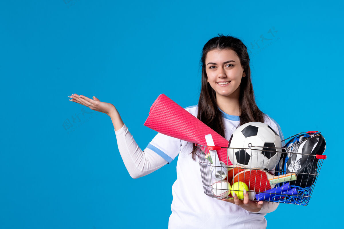 球员前视图：年轻女性在蓝色墙壁上运动购物后拿着篮子前面年轻女性水平