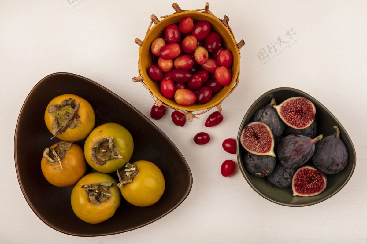 观点顶视图甜黑色无花果在一个碗上与山茱萸樱桃在一个桶柿子水果在一个碗上的白色墙壁有机新鲜顶部