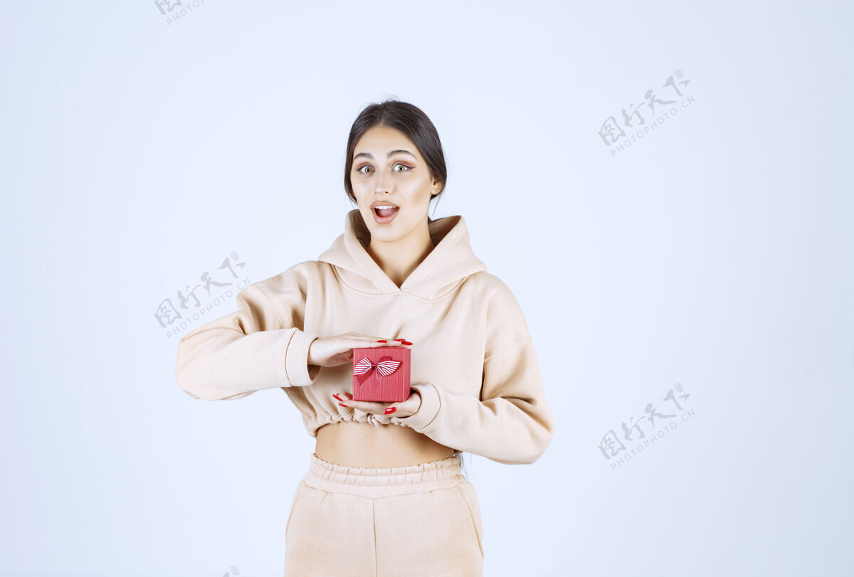 女性年轻女子双手捧着一个红色小礼盒模特成人姿势
