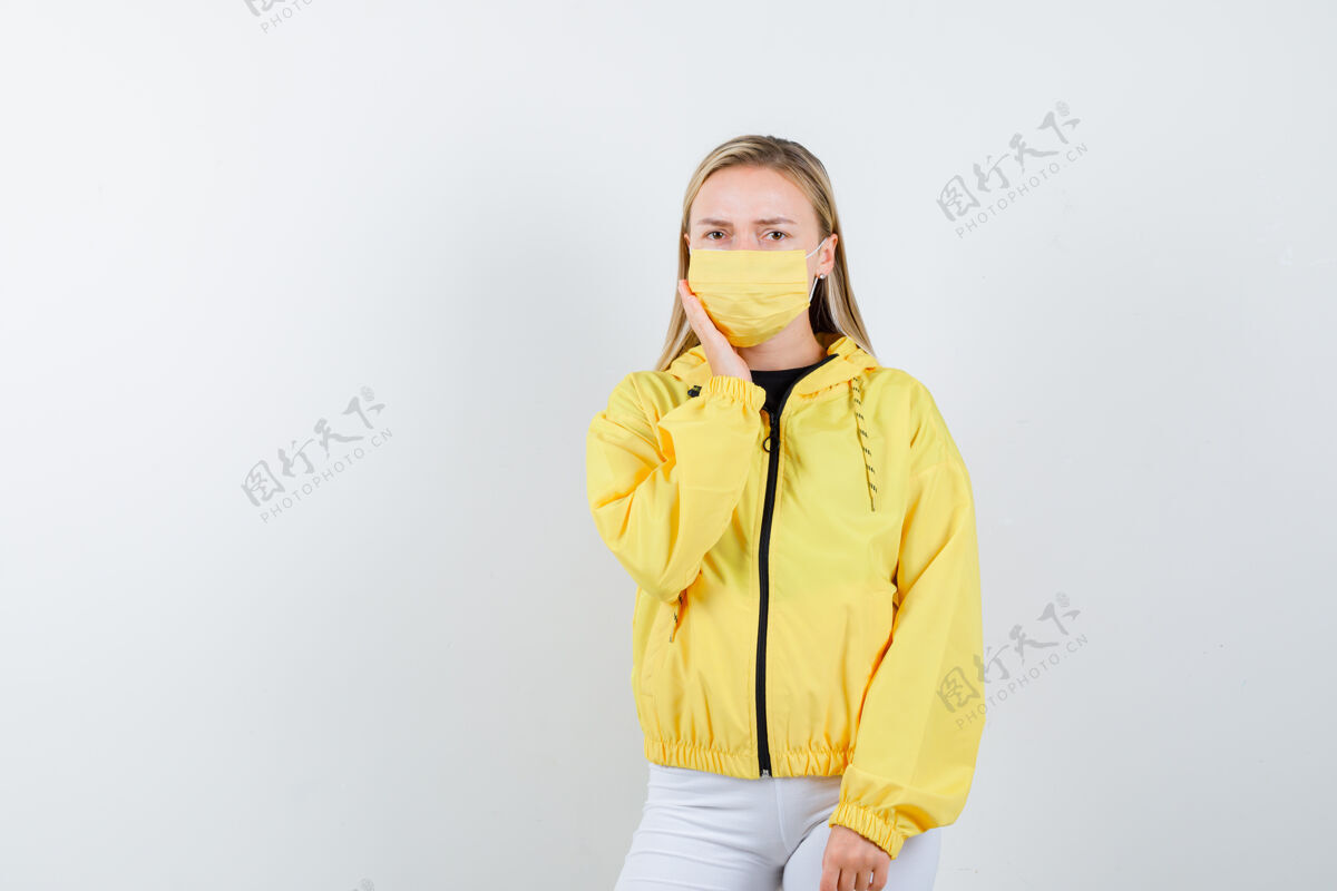 护理年轻的女士穿着夹克 裤子 戴着口罩 牙疼 表情悲伤 前视图夹克面具时尚