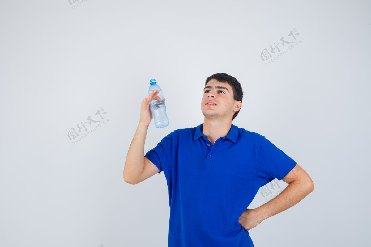 年轻一个穿着t恤的年轻人手里拿着塑料瓶 手放在腰上 看上去很自信 正对着前方青春学校腰