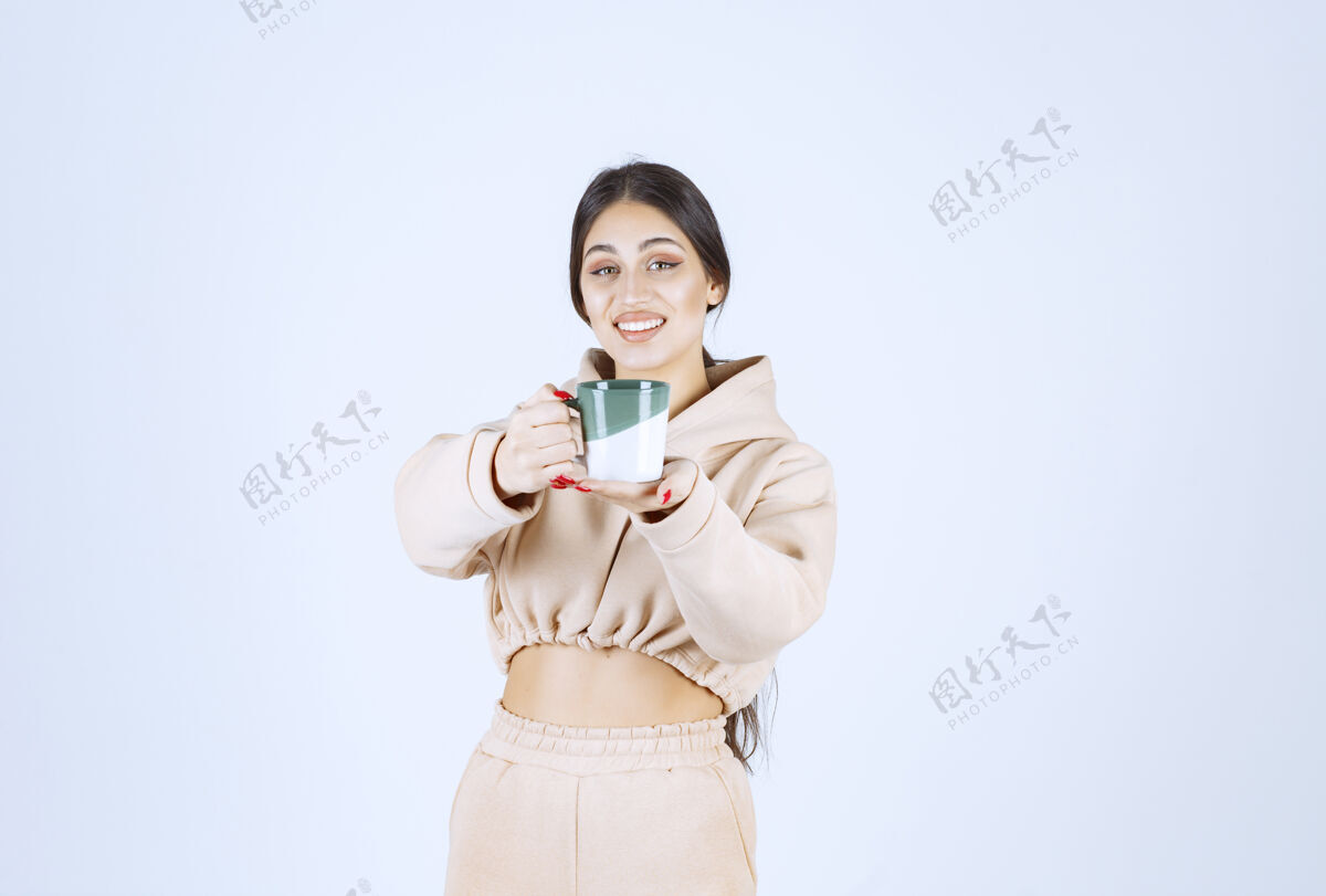 模特一个年轻的女人在一个绿色的杯子里提供咖啡人类年轻女人