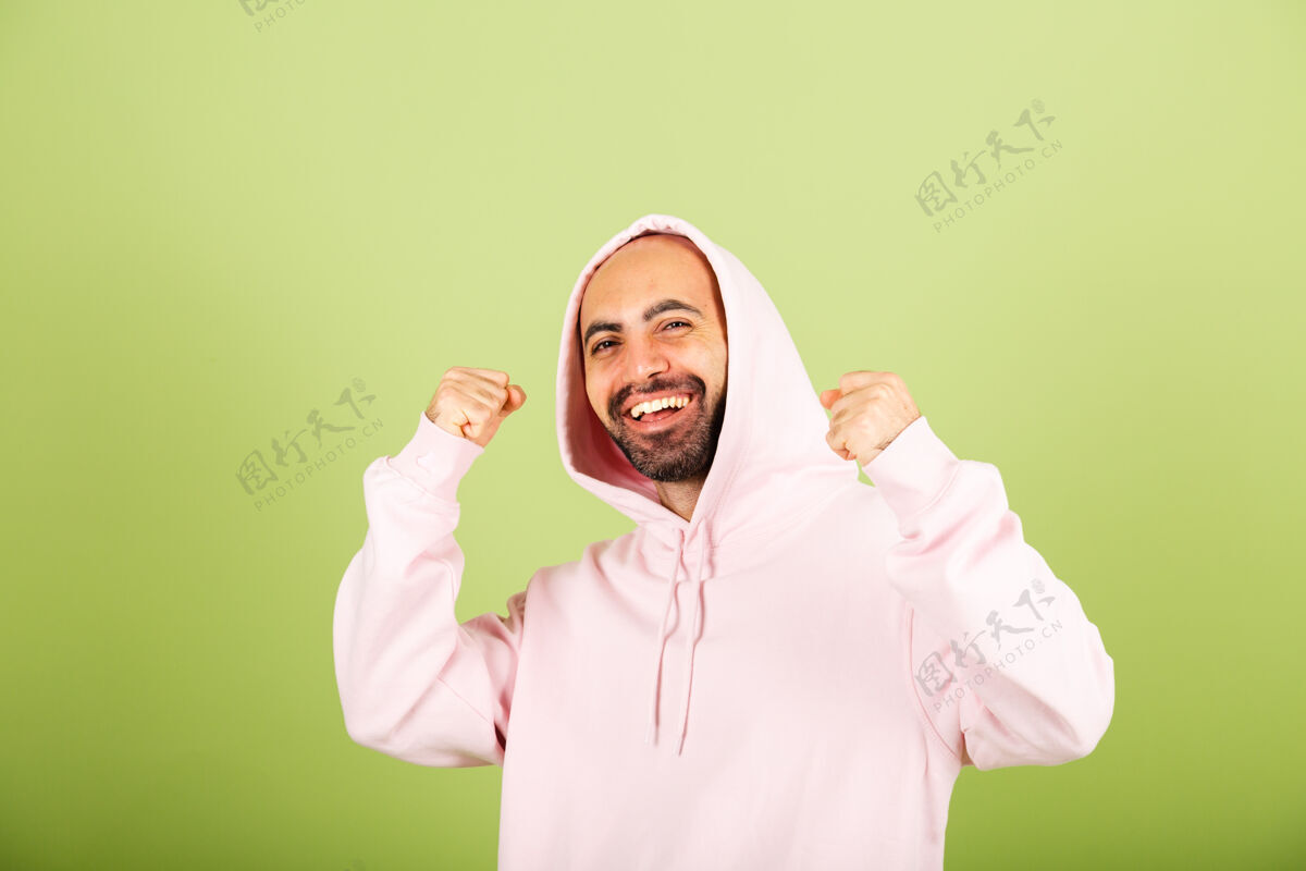 有趣年轻的白人男子在粉红色连帽衫孤立 快乐握紧拳头与赢家手势成功快乐单身尖叫