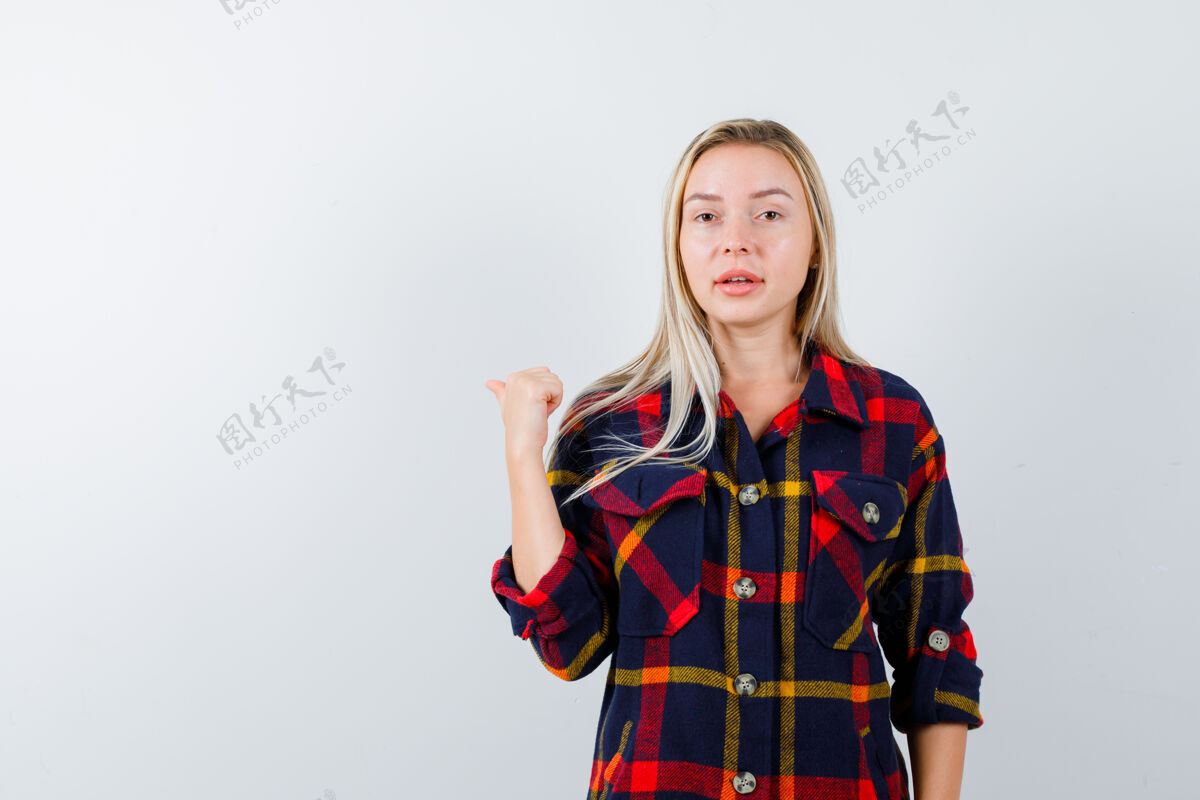 指尖穿着格子衬衫的年轻女士用拇指指着后面 看上去很自信 正对着前方女孩自然亚洲人