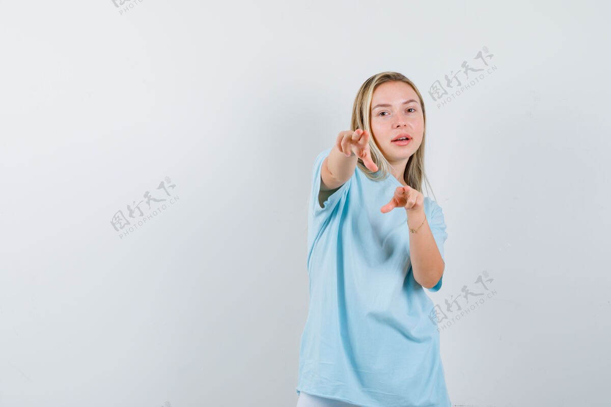 积极穿着蓝色t恤的金发女孩用食指指着摄像机 看上去很自信 正面照快乐时尚目录