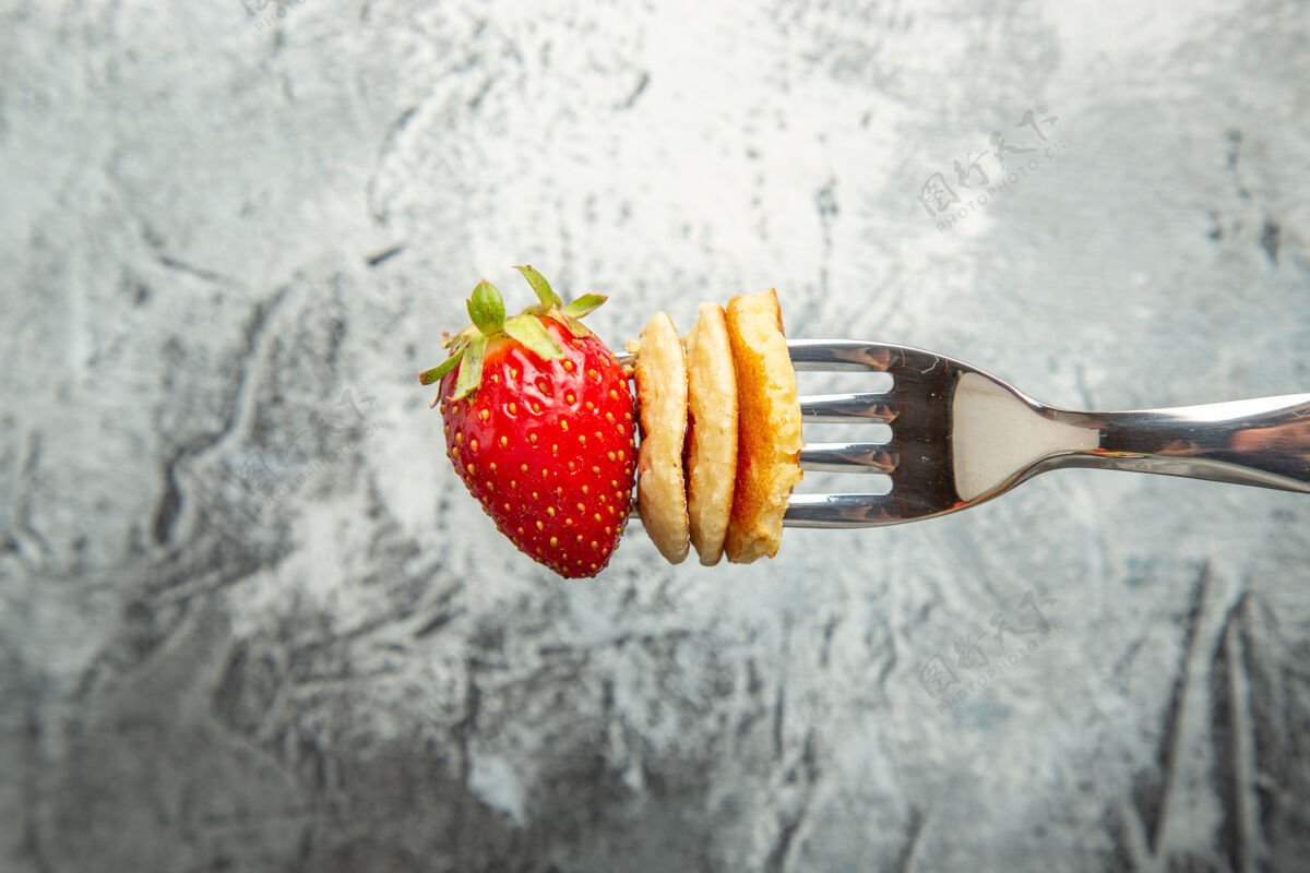 新鲜前视小煎饼与草莓叉子和轻表面蛋糕水果甜点成熟食物清淡