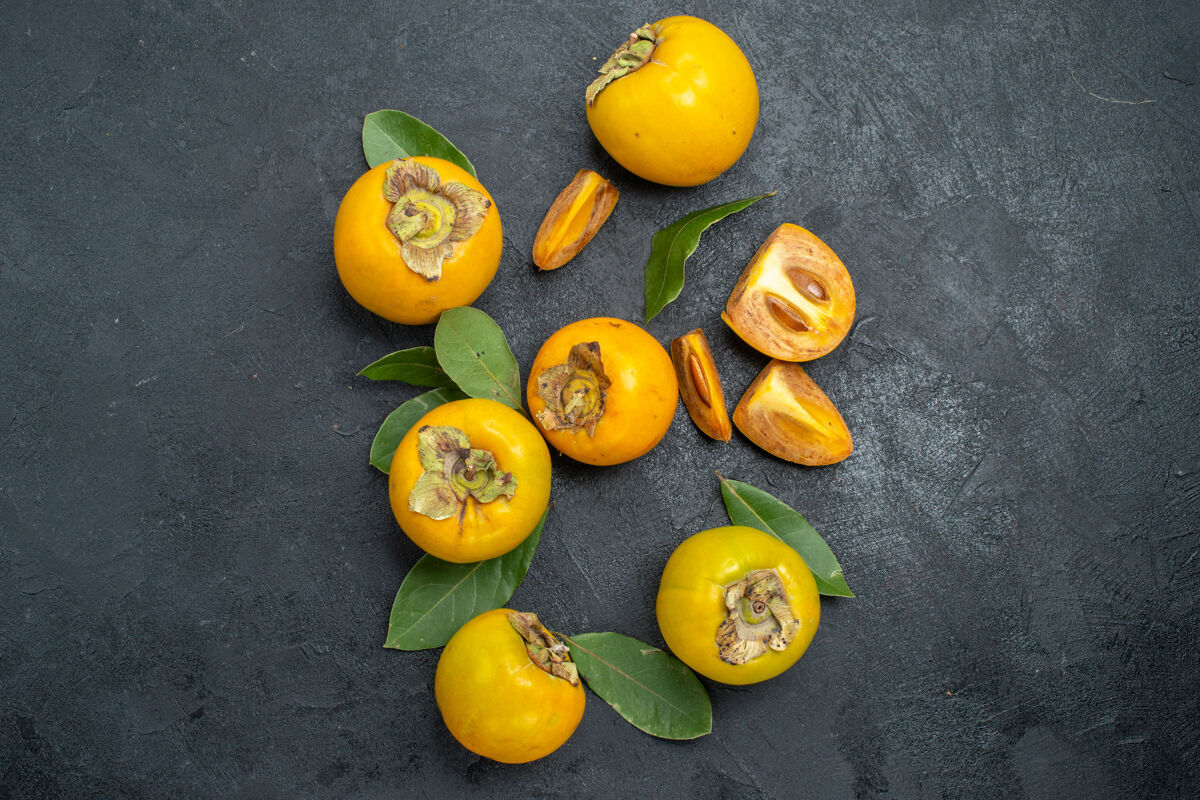 味道顶视图新鲜甜甜的柿子 叶上深色的桌子上成熟的水果味道顶部柑橘成熟