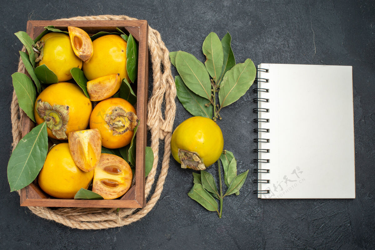 笔记本顶视图新鲜甜甜的柿子在盒子里放在深色桌上成熟的水果味食物成熟柑橘