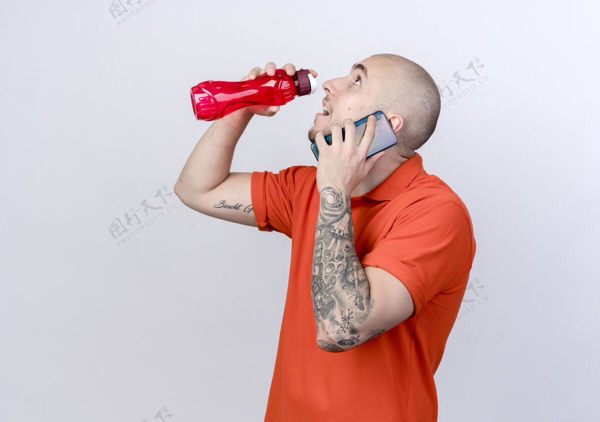 说话抬头看着年轻的运动型男子在电话里讲话举起白色墙壁上孤立的水瓶男人年轻手势