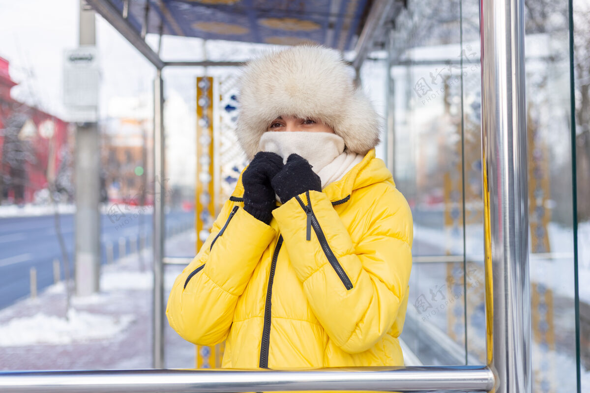 女孩在寒冷的日子里 一个穿着冬衣的女人在公共汽车站等公共汽车电车寒冷坐着