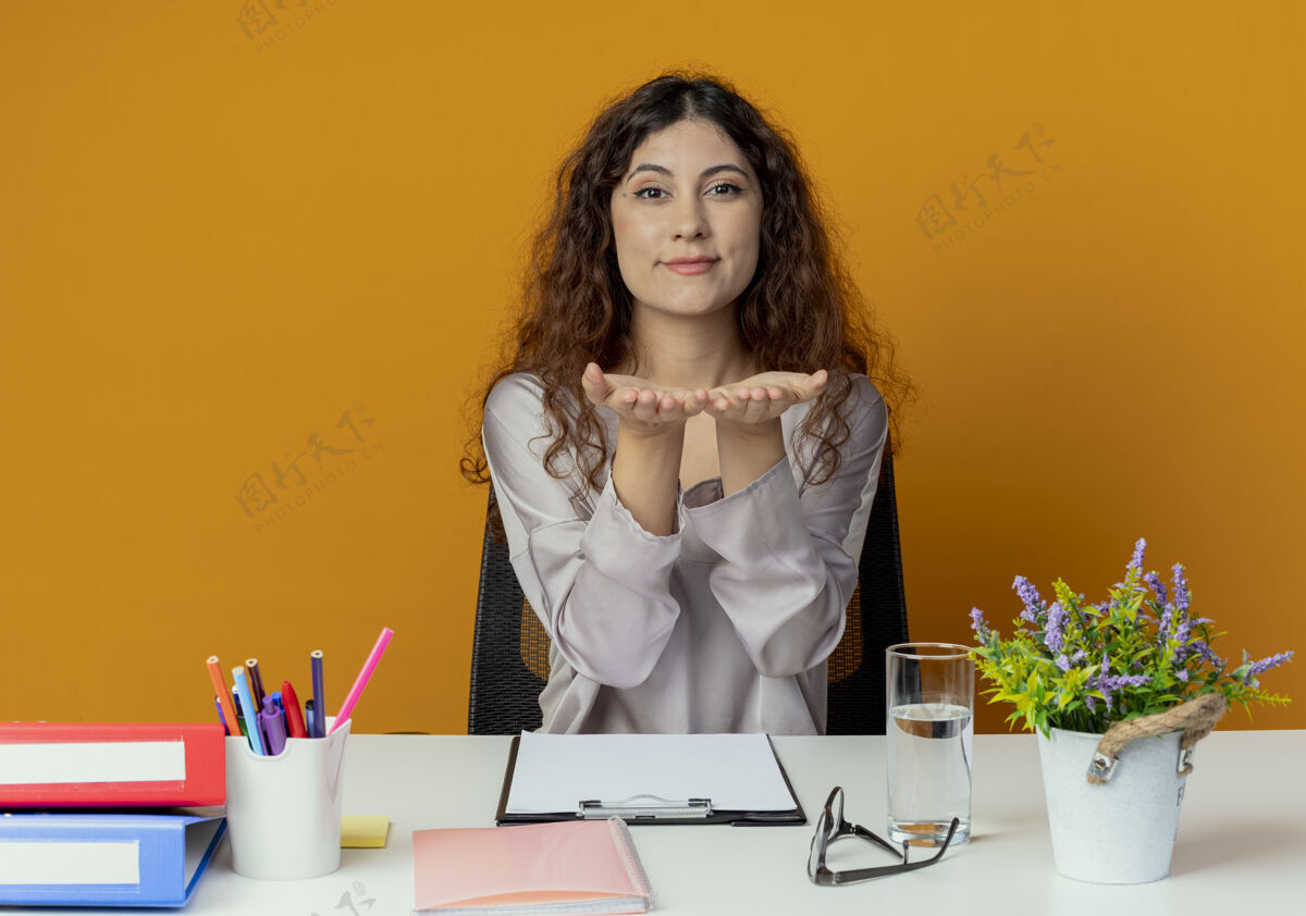 工具年轻漂亮的女上班族坐在办公桌旁 手里拿着办公工具 手里拿着相机 孤零零地站在橘子上手工人请