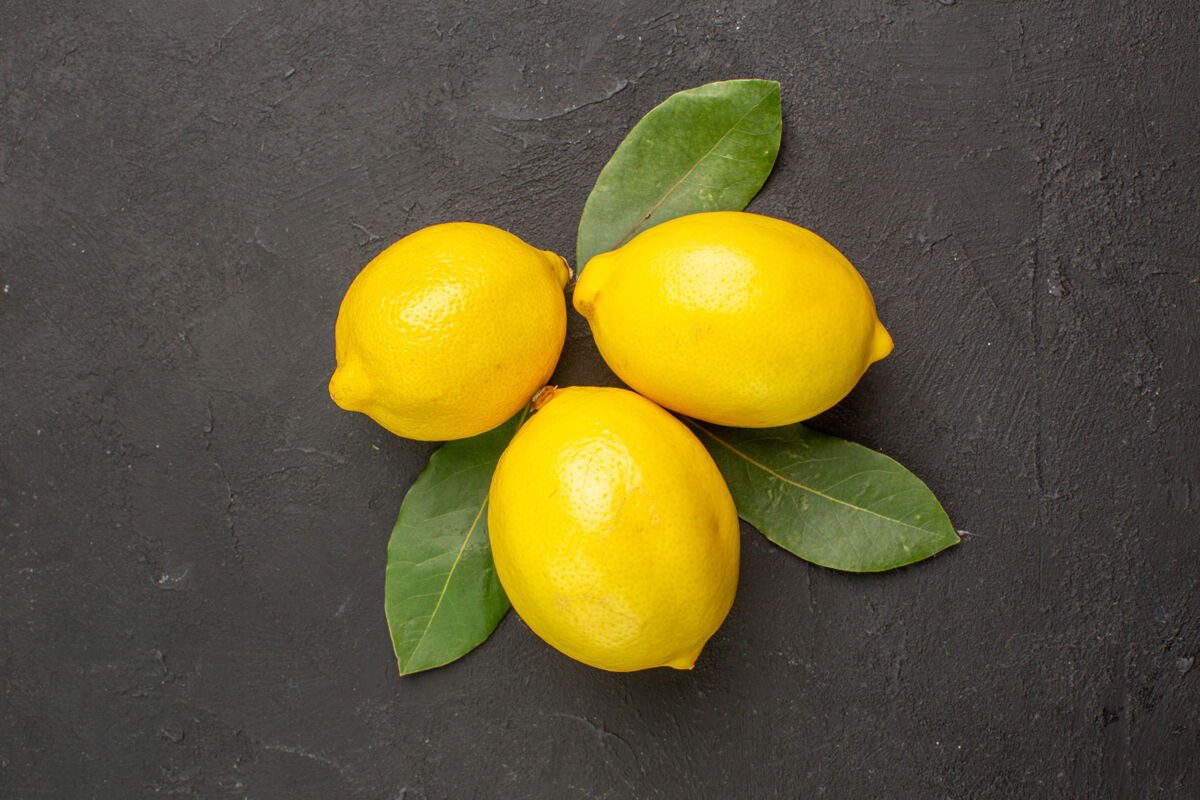 叶子顶视图新鲜的酸柠檬和叶子放在深色的桌子上柑橘黄色的水果顶部柠檬多汁