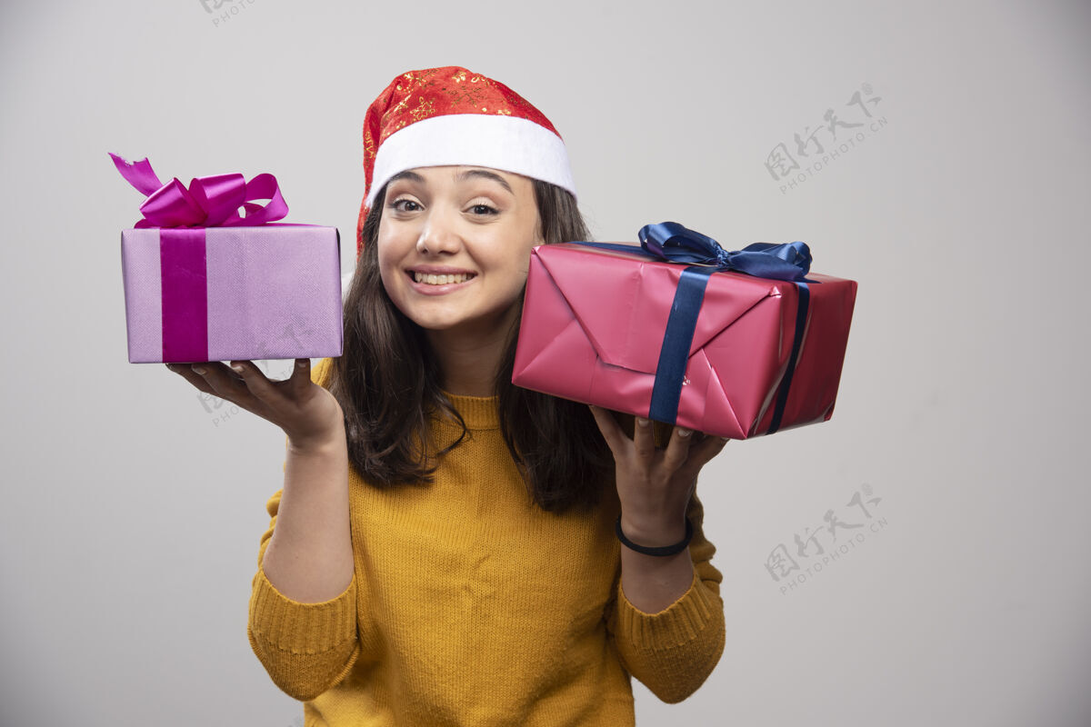 礼品盒戴着圣诞老人红帽子的年轻女子 手里拿着圣诞礼物圣诞老人人类微笑