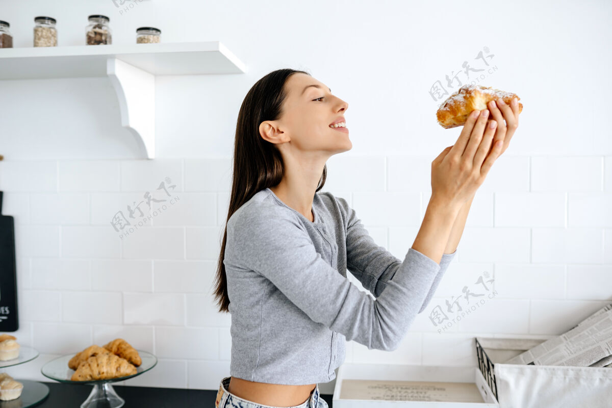 不健康喜洋洋的女人在家吃美味的羊角面包的画像快乐瘦甜点