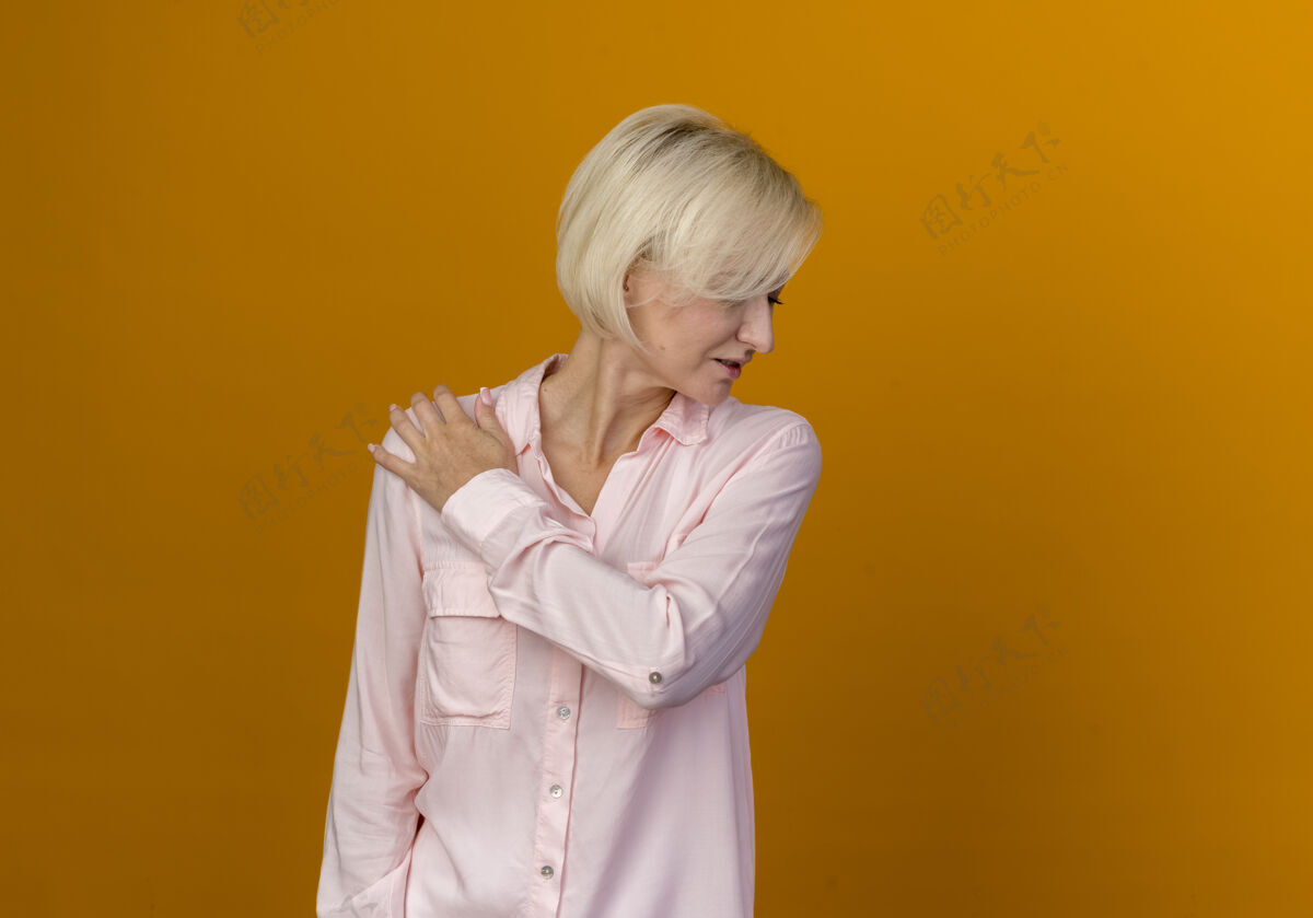 橙色低头 年轻的金发斯拉夫女人把手放在肩膀上 孤立的放在橙色的空间里头空间女人