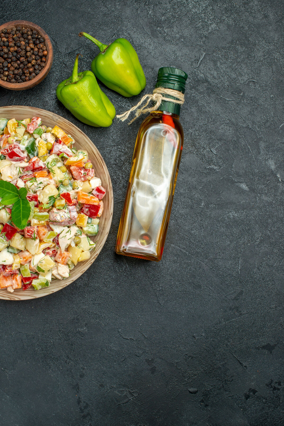 蔬菜一碗蔬菜沙拉的俯视图 灰色背景上有一碗蔬菜和胡椒油瓶以及甜椒碗美食胡椒